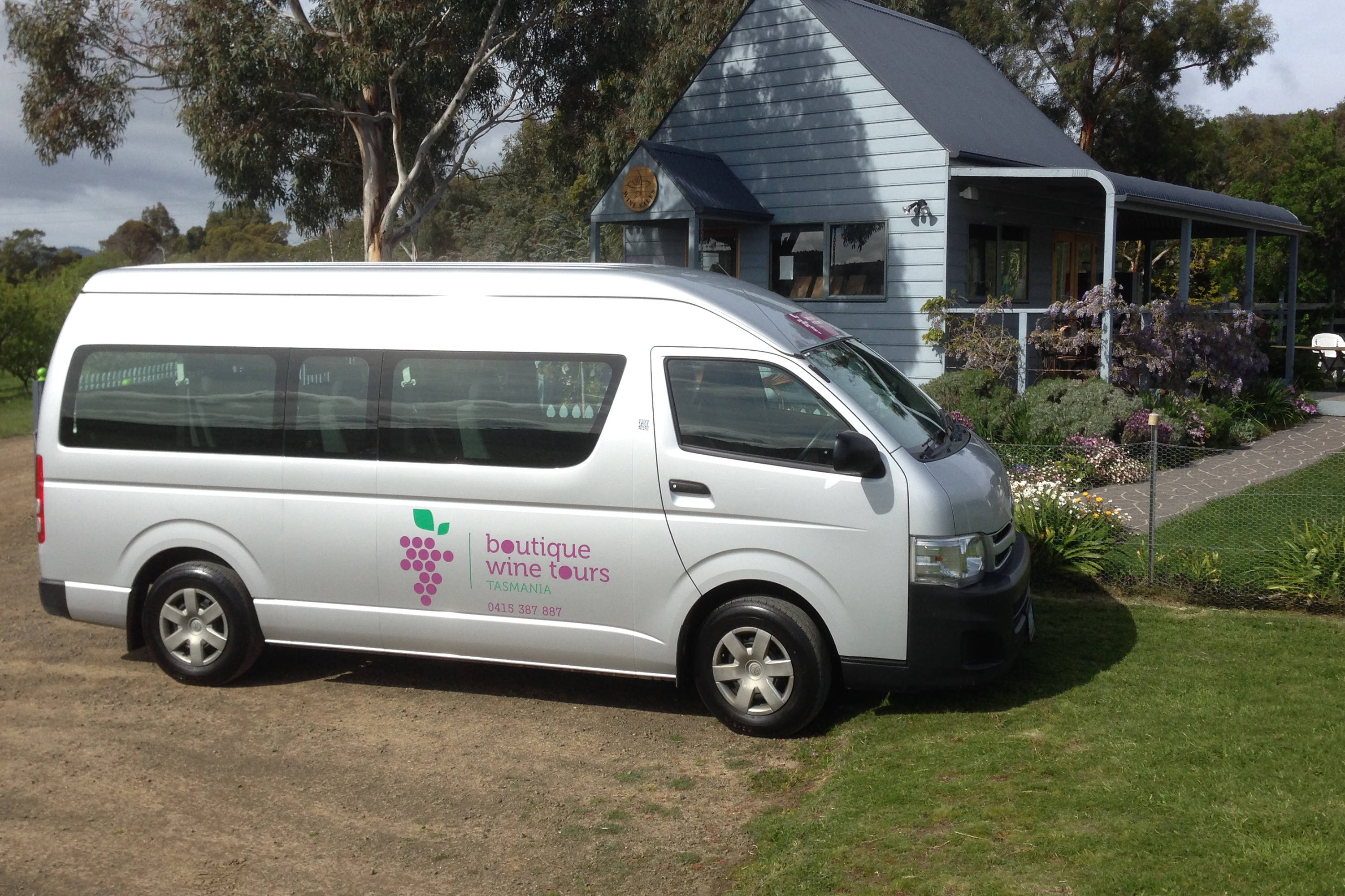 The silver Boutique Wine Tours Tasmania van with the logo on the side in purple and green.